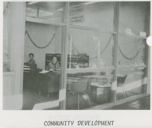 Two unknown women are seated at desks inside the Community Development room in Denton City Hall. The photo appears in the December 1969 city employee newsletter, The Spotlight.